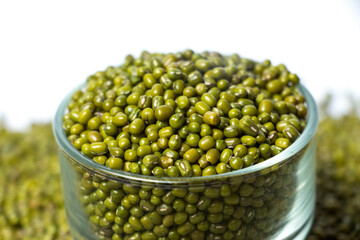 Closeup of Green Moong Dal beans in a Glass Bowl Isolated on a white background. The mung bean or green gram (Vigna radiata).