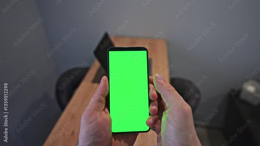 Poster person using smartphone with green screen in office. scrolling on the screen with his thumb. the gre