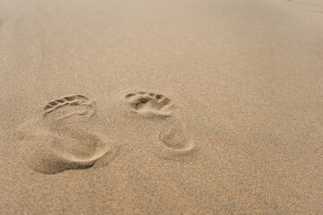 Footprints of bare feet in the dry sand, close up
