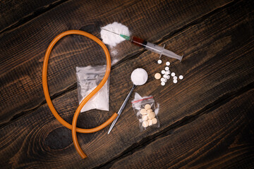 Syringe with drugs dose and medical tourniquet on black background. Narcotic substances in spoon....