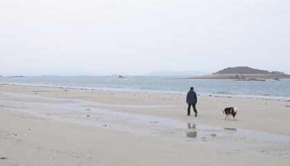 Un homme qui promène son chien sur une plage en Bretagne