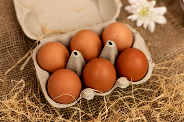 Organic brown eggs in an egg carton. Eggs in a box on straw. Broken Egg