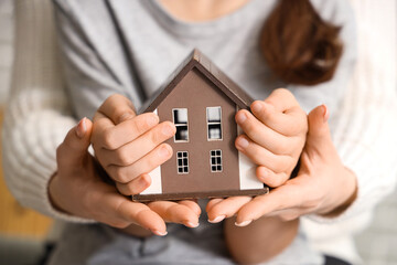 Woman with adopted girl holding house model at home, closeup