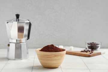 Wooden bowl of coffee powder with geyser coffee maker on white tile table