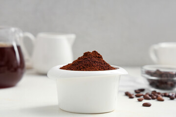 Bowl of coffee powder with beans on light background