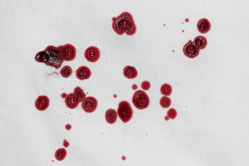 Drops of blood stains on white fabric. blood splatters on clothes. red dripping blood spatters