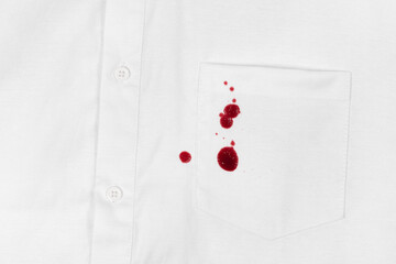 Drops of blood stains on white shirt with a pocket. red dripping splatters on white fabric. blood splatters on clothes.