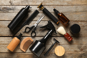 Modern trimmer with bottles of cosmetic products and brushes on wooden background