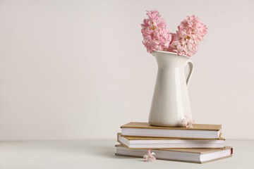 Vase with beautiful pink hyacinth flowers and books on white background