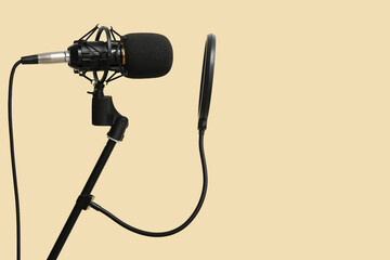 Stand with professional microphone on beige background