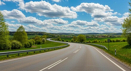 Scenic Country Road Winding Through Lush Green Landscape Under a Sunny Sky with Fluffy Clouds