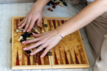 Woman Mixing Chess Pieces on Backgammon Board.