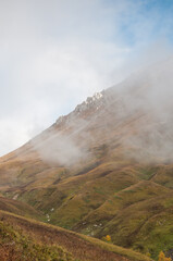 Grass-covered slopes of the Mount Oshten in autumn covered with morning fog, Republic of Adygea,...