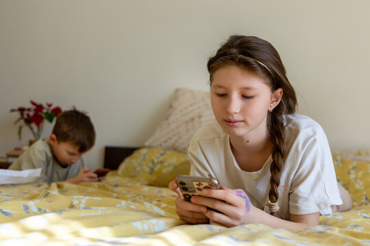 Kids lying on bed using smartphones. - Powered by Adobe