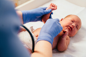 Nurse in gloves checking newborn baby foot reflexes