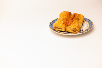 two sausage rolls on a blue and white plate, plenty copyspace