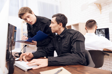 A man guard is sitting in front of the monitor.