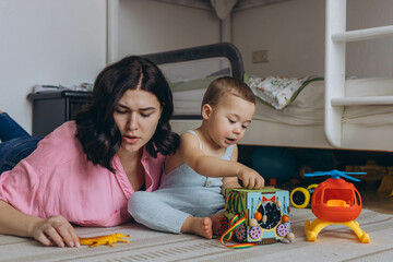Mother and baby playing together with developmental toys,sitting in floor,fostering learning