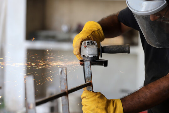 
Man cutting metal with a grinder wearing protective gear - Powered by Adobe