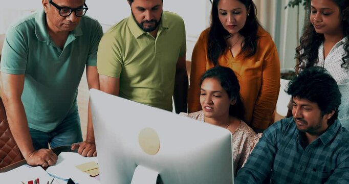 Indian Asian young business professionals or startup partners collaborating on an important project, working intently on computer in office, every team member involved in discussions, decision-making