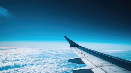 Obraz premium A beautiful aerial shot of an airplane wing, with the endless blue sky creating a serene and peaceful view.