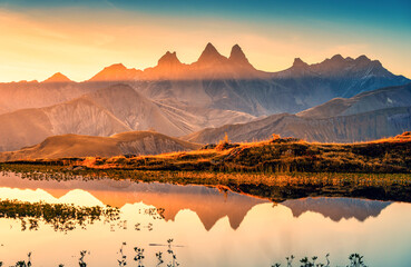 Sunrise shines over Lac Guichard with Arves massif and lake reflection in autumn at Aiguilles d'Arves, French Alps, France