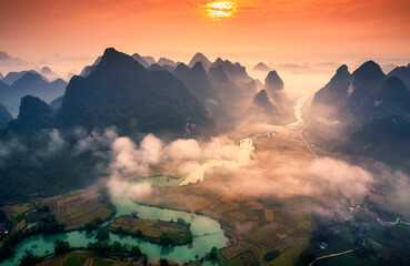 Sunrise over mountain range with foggy on rural village and river flows through in Phong Nam Valley at Vietnam