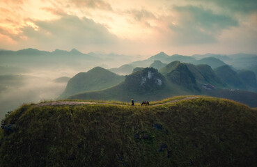 Scenery of Ba Guang grass hill, Mountain range with fog and villager bringing horse to graze on the mountain in the morning
