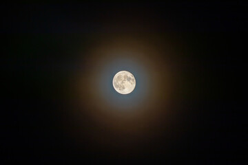 Full moon close-up. Multi-colored glow around the moon - In meteorology, a corona (plural coronae) is an optical phenomenon produced by the diffraction of moonlight