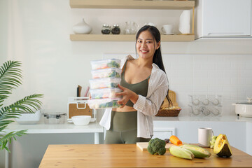 Beautiful young woman preparing healthy meal in clear plastic storage boxes. Nutritious and healthy lifestyle concept.