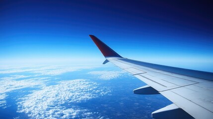 Obraz premium A sleek airplane wing in flight, with a brilliant blue sky creating the perfect backdrop for this aerial view.