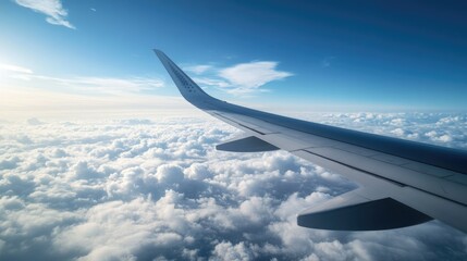 Fototapeta premium A stunning view of an airplane wing above the clouds, with a brilliant blue sky and a few wispy clouds below.