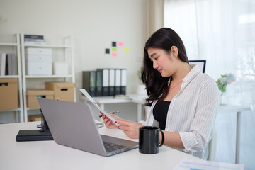 Young entrepreneur sitting at her desk while analyzing financial reports in a modern office.