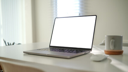 Fototapeta premium Contemporary office setup with a laptop displaying a blank screen, a warm coffee mug, and a neat workspace.