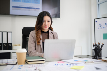 Businesswoman reviews documents and charts at modern office.