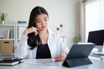 Stylish businesswoman thoughtfully examining paperwork while working in a well-organized and modern office environment.