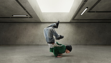 Performer holding freeze upside down, showing himself through movement against gray concrete wall....