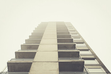 Low-angle view of a tall beige building with numerous balconies, showcasing architectural lines and a minimalist aesthetic, representing urban modernity and simple elegance