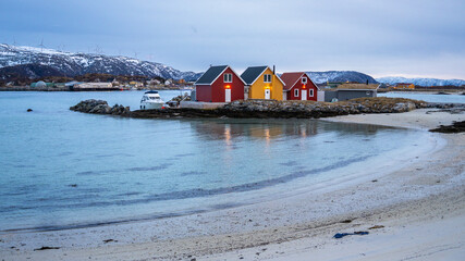 three beautiful, colorful houses on the shore of the North Atlantic. wooden holiday homes on the islands of Hillesøy and Sommarøy. red and yellow house by the lake. Holidays in Troms, Northern Norway.