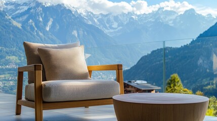 Fototapeta premium A warm wooden armchair with a comfy pillow sits next to a round table on a balcony, with a stunning mountain range in the background.