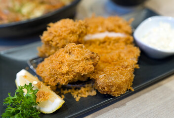 Fried oyster and loin katsu set served on black plate with a bowl of rice