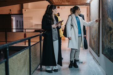 People discussing and analyzing artwork on display in a museum environment. The scene portrays...