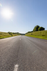 an empty straight paved road against a blue sky background