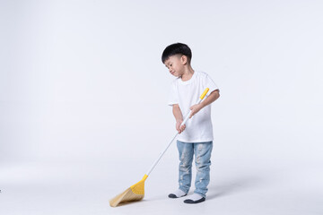 Asian boy doing chore by sweep the house floor with plastic broom