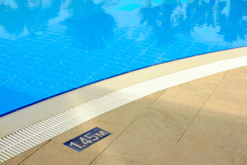 Obraz premium Swimming pool with depth marker and clear blue water highlighting safety and inviting atmosphere for relaxation in a tropical resort setting