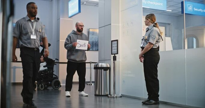 Transportation Service in International Airport Terminal: Airport Greeters Holding Name Sign, Waiting for Passengers From Plane Flight. Diverse People and Travelers Walking with Luggage. Full Shot.