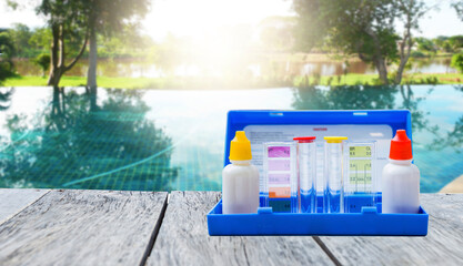 Water tester test kit on wooden table over blurred resort swimming pool background, swimming pool service and maintenance © sirirak