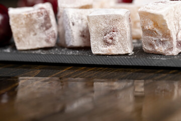 sweet lukum slices with cherry slices on a black slate board