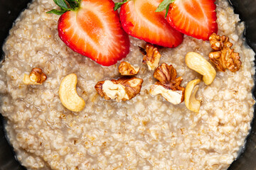 Oatmeal porridge with strawberries and nuts healthy breakfast appetizer dish fresh gourmet food background on the table rustic food top view copy space keto and paleo diet vegetarian and vegan food