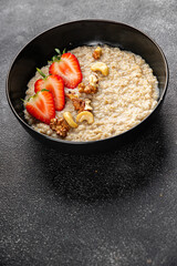 Oatmeal porridge with strawberries and nuts healthy breakfast appetizer dish fresh gourmet food background on the table rustic food top view copy space keto and paleo diet vegetarian and vegan food
